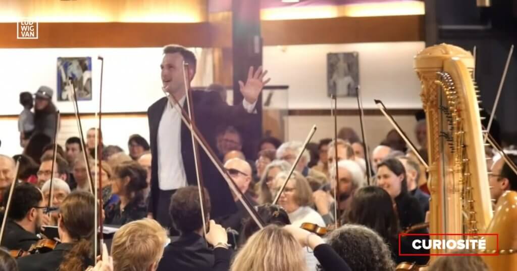 Andrei Feher surpris par les cloches de l'église St-Marcel alors qu'il vient de donner le dernier accord de la symphonie. (Photo : capture d'écran de la vidéo disponible sur le Facebook de l'orchestre Ondes Plurielles)