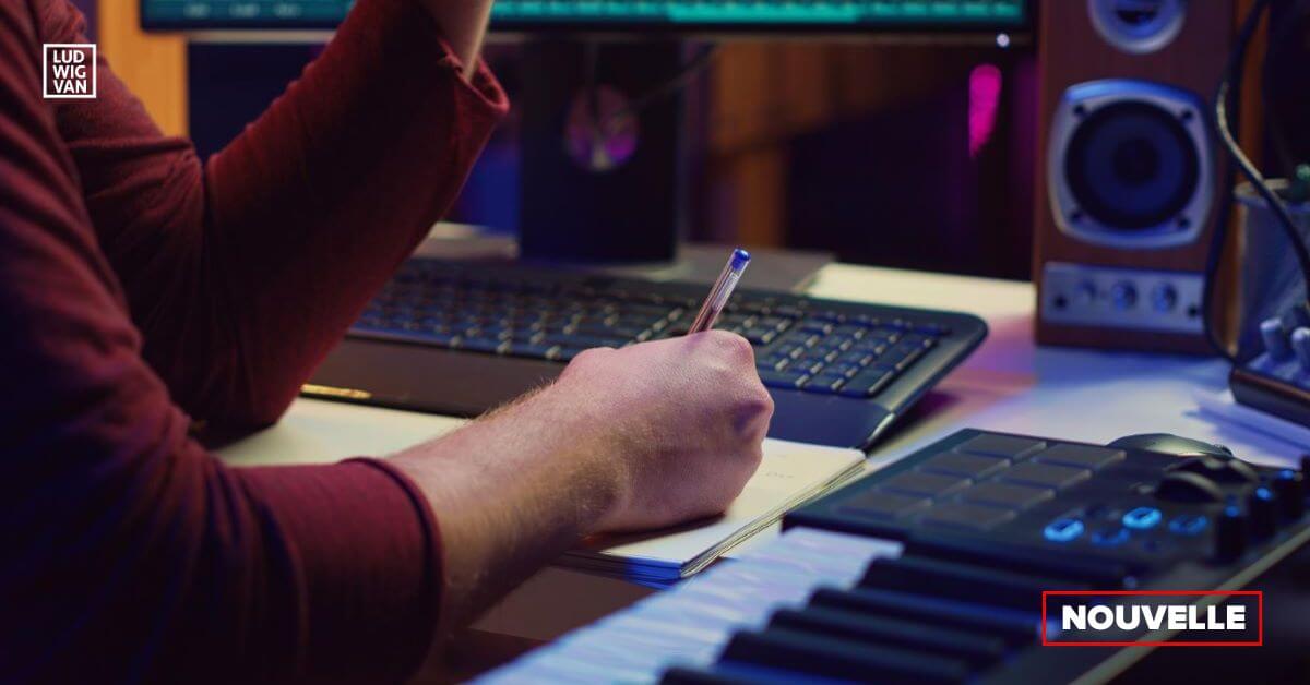 un bras posé sur un bureau couvert de matériel informatique et d'un clavier pour composer à l'ordinateur, 