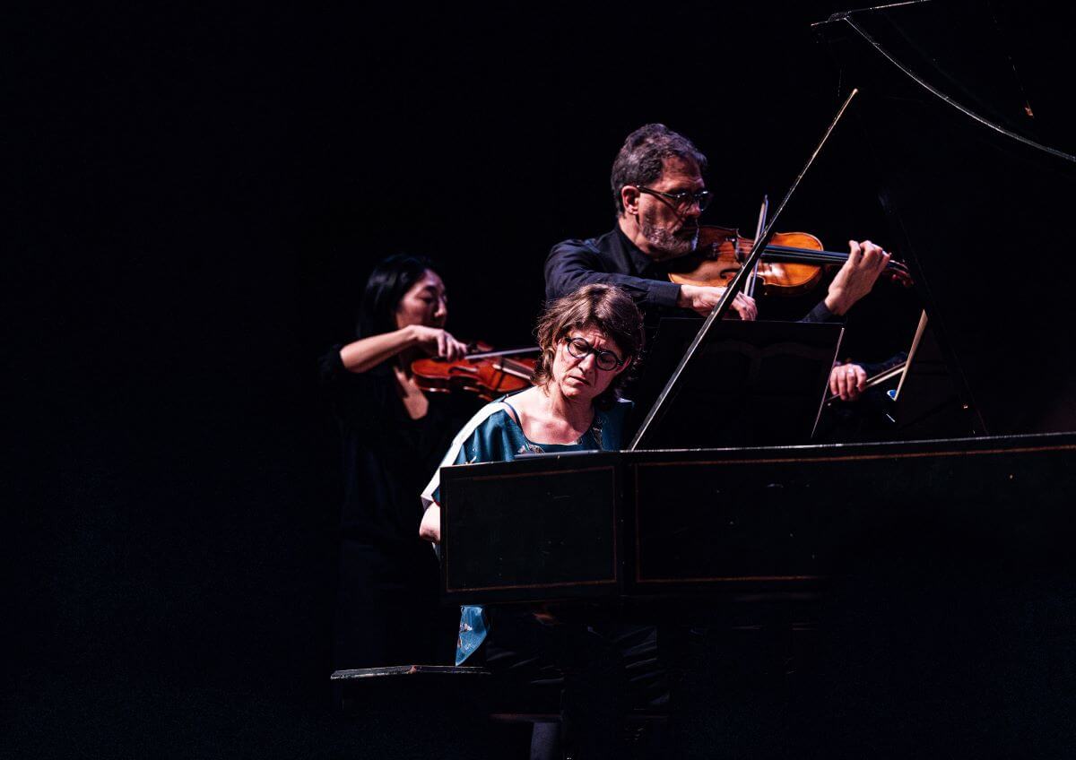 Les deux membres de Café Zimmermann, Céline Frisch en tant que soliste au clavecin, et Pablo Valetti menant l'orchestre au violon, la membre d'Arion Sari Tsuji attentive derrrière lui. (Photo : Annie Éthier)
