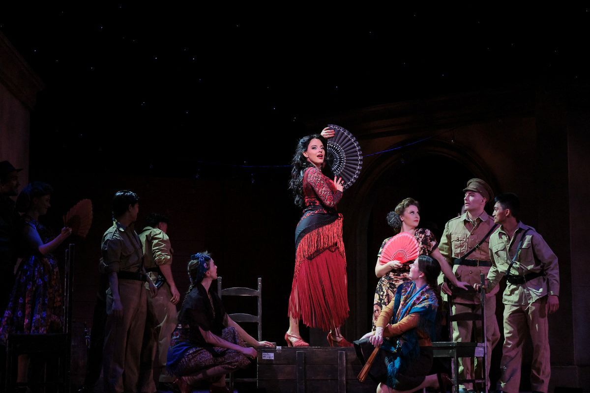 Rihab Chaieb en Carmen, debout sur une chaise, un éventail rouge déployé, dans la production de l'Opéra de Montréal. (Photo : Vivien Gaumand)
